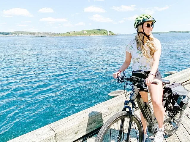 A woman riding an e-bike along the waterfront overlooking the harbor