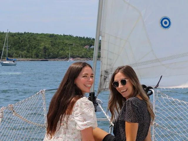 Deux femmes souriantes profitent d’une excursion en voilier sur l’eau à Halifax.