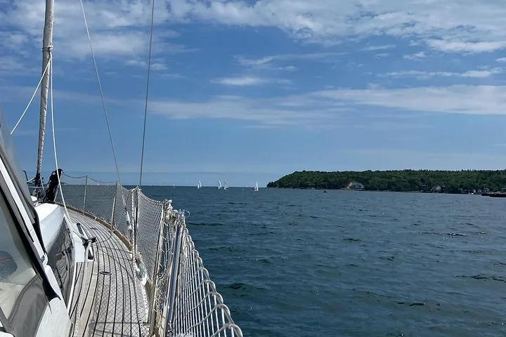 Vue au-delà du pont d'un voilier vers d'autres voiliers au loin.