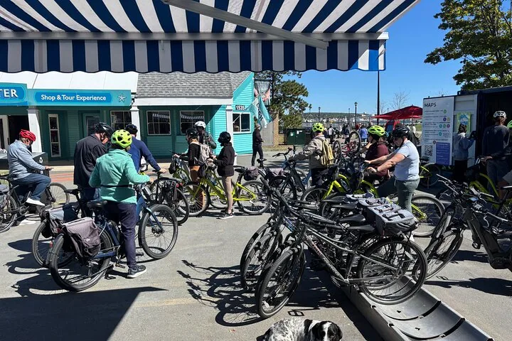 Personnes se rassemblant avec des vélos devant un magasin par une journée ensoleillée.